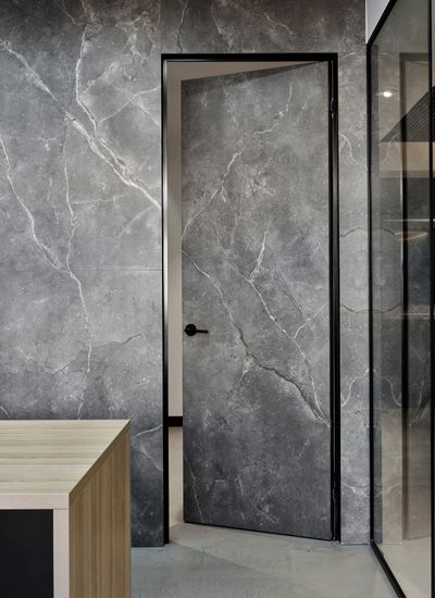 Modern interior with a gray marble look sintered porcelain door and stone walls.