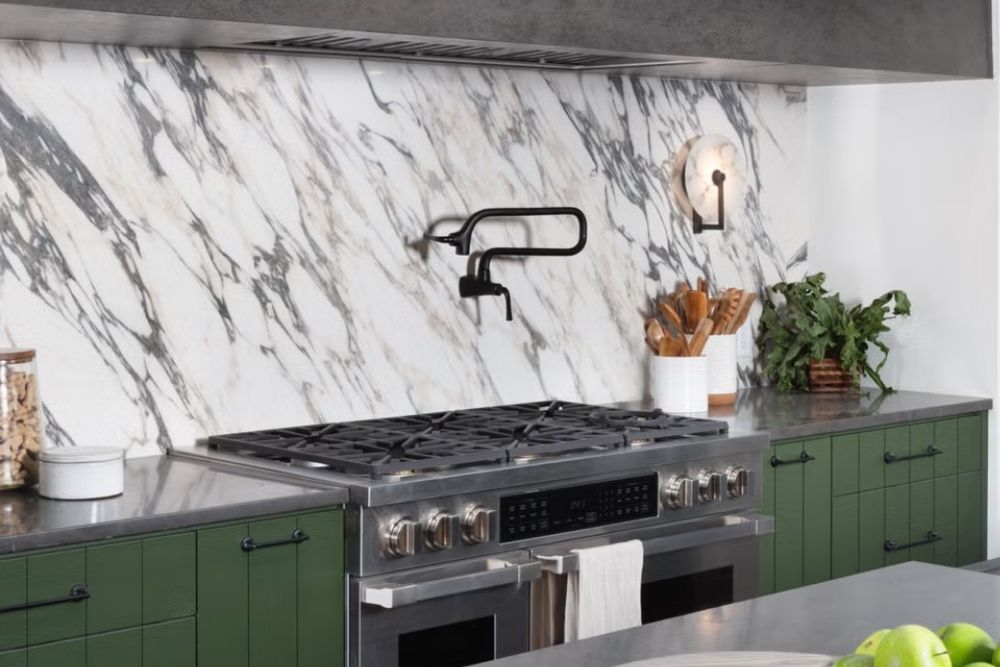 Modern kitchen with sintered stone backsplash and green cabinets and gas appliances